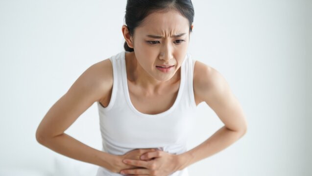A woman experiencing stomach pain, clutching her abdomen with a worried expression on her face, conveying a sense of discomfort and distress.