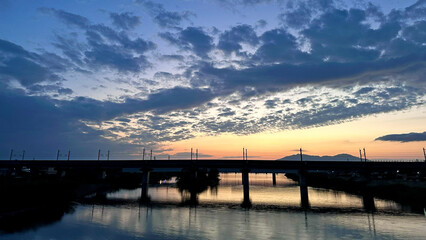 Fototapeta premium Evening view of Nakanokuchi River and railway bridge from Sado Bridge in Tsubame City, Niigata