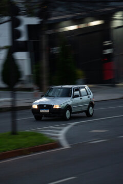 Silver fiat uno driving at dusk on city street, Classic compact economy car in motion on urban cenario