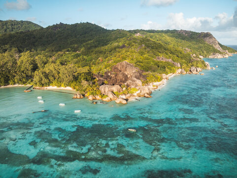 Aerial view of Anse Source d'Argent beach with turquoise waters, iconic granite rock formations, and lush tropical hills in L'Union Estate, Seychelles.