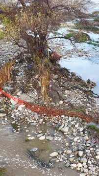 Aerial shot of flood damage and trash in the Los Angeles River after heavy rains. Vertical Video.