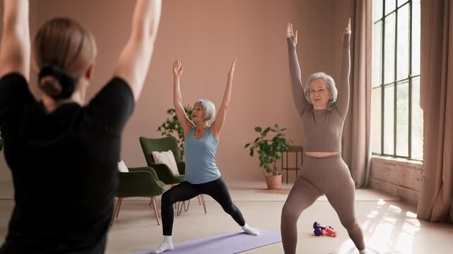 Smiling senior women performing warrior pose during yoga class with trainer