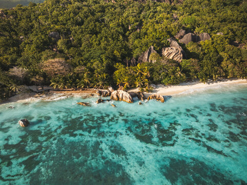 Aerial view of Anse Source d'Argent beach with turquoise water, granite rock formations, and lush tropical forest in L'Union Estate, Seychelles.