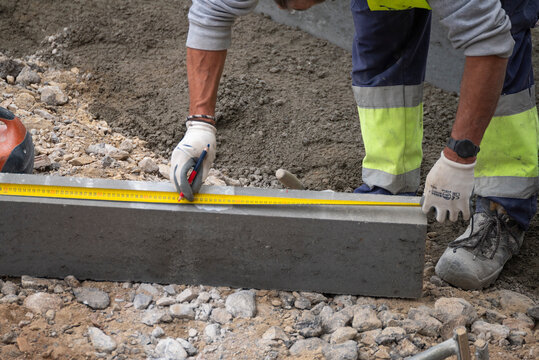 Worker measuring concrete curb with yellow tape measure The Concept of accuracy and planning