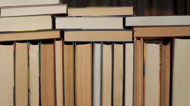 Books Stacks Build Stop Motion, Horizontal stacks of hardcover volumes showing page edges background, Multiple books arranged flat, visible paper blocks, studio lighting, symmetrical layout
