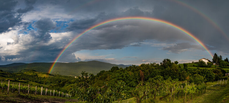 vista panoramica su di un ambiente naturale tra Italia e Slovenia con un bellissimo arcobaleno totale, di pomeriggio, durante un temporale estivo