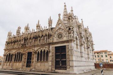Fototapeta premium Gothic architecture of Santa Maria della Spina church with spires, statues, and intricate details along the Arno river in Pisa