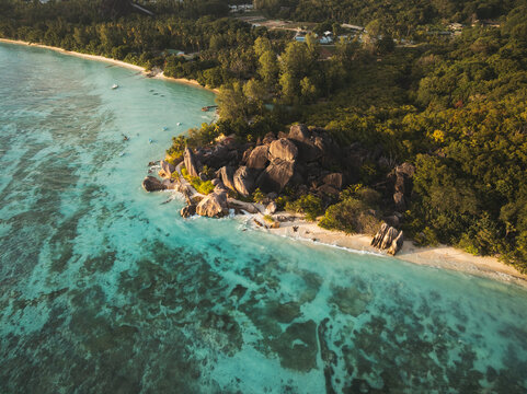 Aerial view of Anse Source d'Argent beach featuring iconic granite boulders, turquoise coral reefs, and lush tropical forest in L'Union Estate, Seychelles.