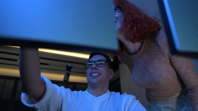Two software developers collaborating at night, focusing on code review and debugging process on a computer screen, representing teamwork, innovation, and modern software development workflow.