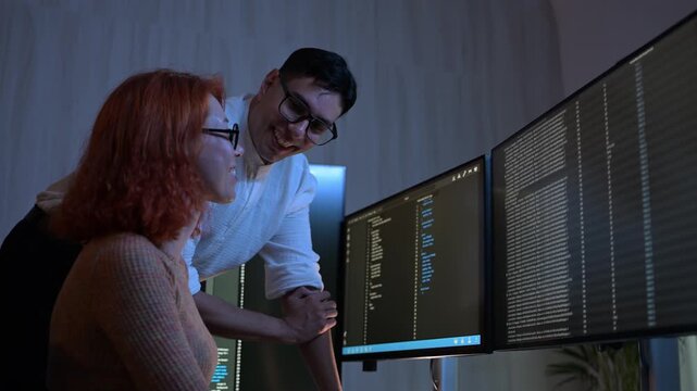 Two software developers collaborating at night, focusing on code review and debugging process on a computer screen, representing teamwork, innovation, and modern software development workflow.