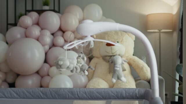 Soft pastel balloons and plush teddy bear create serene nursery atmosphere with spinning crib mobile featuring animal toys promoting comfort innocence and care. Infant child family love parenthood