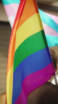 Rainbow lgbt flag on shoulder of unrecognizable person during pride parade in European city, vetical video. Bright symbol of lgbtq community in pride month during special event.