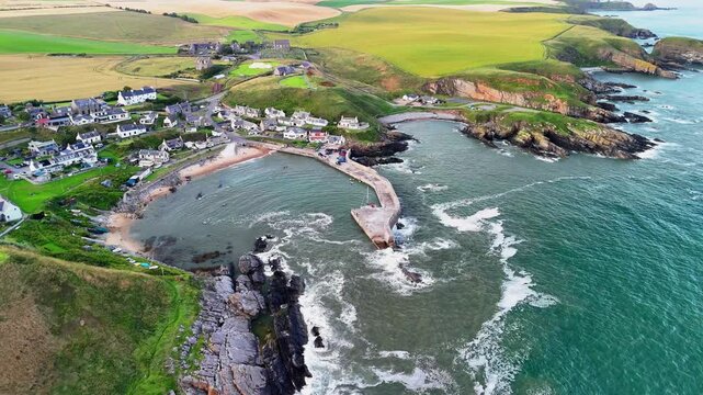 Aerial orbit shot of the picturesque Collieston harbour and coastal cliffs, Aberdeenshire, Scotland