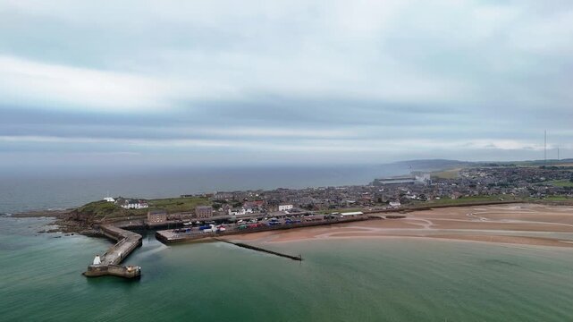Aerial drone approach from Moray Firth sea to Burghead coastal town, Moray, Scotland