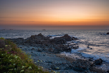 Obraz premium Vibrant sunset over the Atlantic Ocean near Guernsey, Channel Islands, with deep orange and red sky reflecting on calm water.