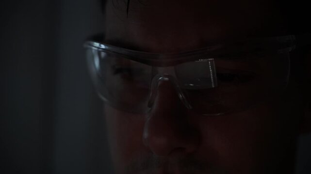 Focused young female software developer programming code on multiple monitors in a dark home office at night. Professional woman engineer working on cyber security and data science tech project.