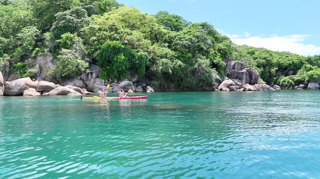 Two women kayaking on the crystal-clear waters of Lake Malawi, enjoying an active and adventurous day in a tropical setting.