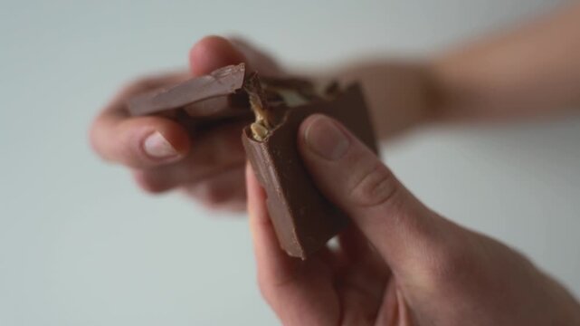 Hands breaking chocolate bar into pieces, sweet snack and dessert concept