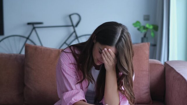 A young woman is deeply distressed after reading something upsetting on her mobile phone. She expresses sadness and covers her face, reacting to difficult news or a painful message received online.