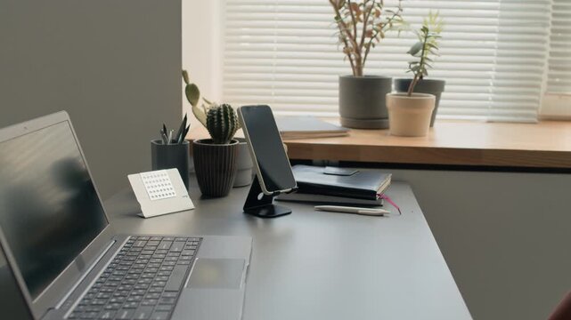 No people tilt up shot of laptop and smartphone on stand on desk in minimalist modern office workstation