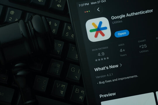 Dhaka, Bangladesh- 28 Oct 2025: An iPad displaying the Google Authenticator app against a judge's gavel and dark keyboard background.