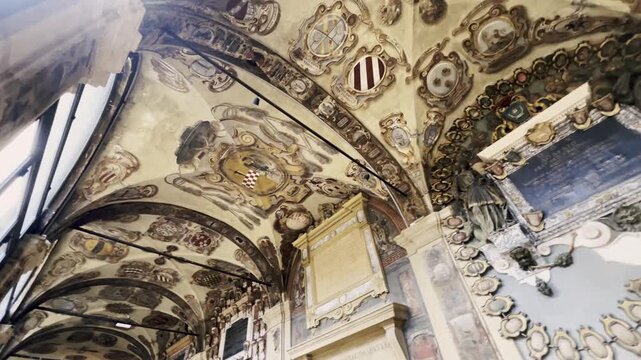 Intricate frescoes and historical coats of arms decorating the vaulted ceilings and walls of the Archiginnasio of Bologna, a renowned landmark and former main building of the university