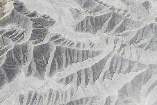 Aerial view of the intricate grey and white eroded ridges and deep canyons of the badlands under soft light Caineville, Utah, United States.