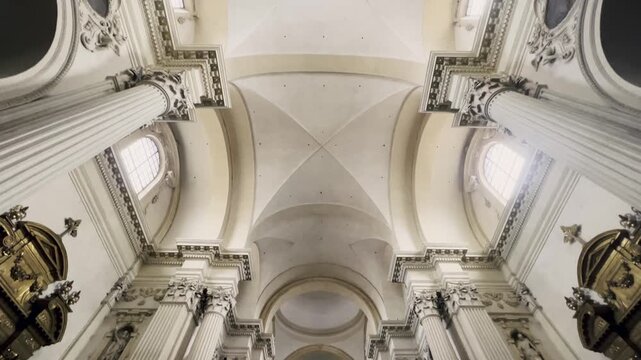 Majestic interior view of a historic baroque church with ornate decorations, massive columns, and a spectacular vaulted ceiling, showing religious art and christian architectural grandeur