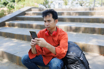 Obraz premium A man in an orange shirt sat on a bench at a coffee shop. He was relaxing, chatting, reading a book, and working—a perfect example of a relaxed lifestyle.