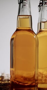 Closeup of a glass bottle full of fresh, homemade, and healthy kombucha tea with wheat moving in slow motion. Healthy, refreshing, and probiotic drink for an organic lifestyle. Vertical