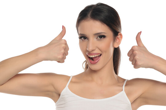 Studio shot of a brunette woman with tied hair wearing makeup, excited happy expression showing double thumbs up, portrait, headshot on a white background
