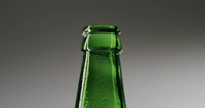 Metal bottle opener uncapping a green glass bottle in a slow-motion macro shot. The golden cap flips off, revealing the top of the beer bottle ready for a refreshing drink at a party