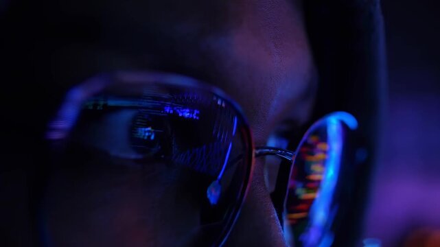 Close-up of glasses reflecting code, capturing a hacker theme. Low-angle shot, video style.