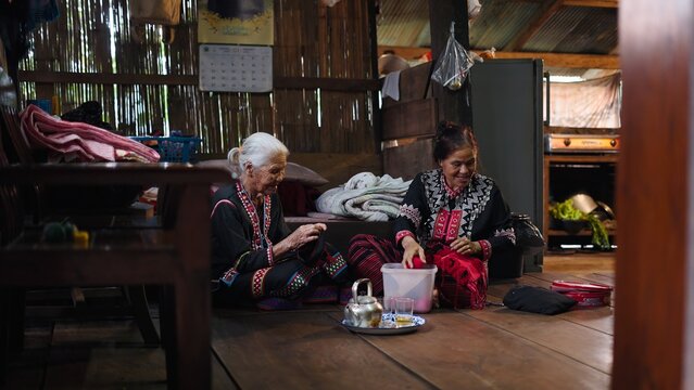 Skilled artisans weaving traditional textiles, elderly women preserving cultural craft in warm, intimate home setting