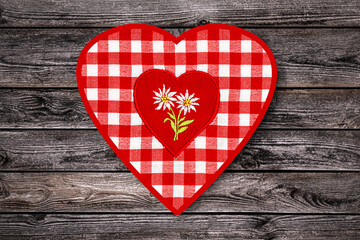 Obraz premium Heart shaped textile with flower design on red and white checkered pattern placed on wooden surface