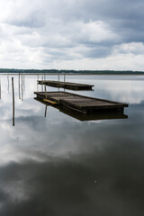 Fototapeta premium Lake of Soustons reflecting a cloudy sky and wooden docks