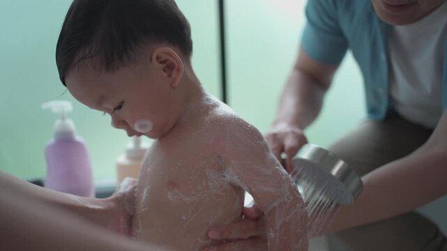 Parents bathing toddler in bathtub with gentle care, family hygiene routine, child safety, warm home lifestyle and nurturing parenting concept