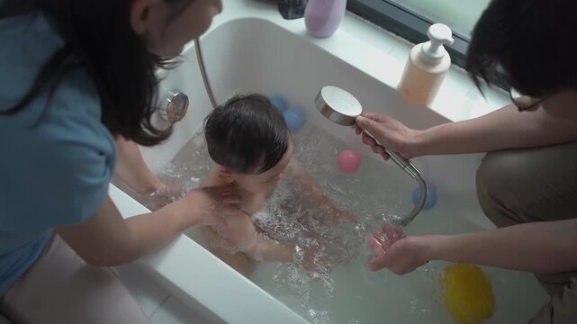 Parents bathing toddler in bathtub with gentle care, family hygiene routine, child safety, warm home lifestyle and nurturing parenting concept