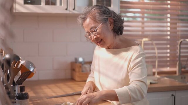 Senior woman preparing food in cozy kitchen with warm sunlight, healthy home cooking, independent elderly lifestyle and wellness living concept