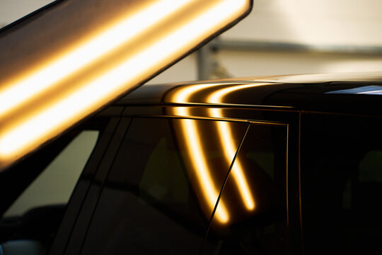 Close-up PDR dent reflection. Specialized PDR light exposes sharp dent on vehicle body line.