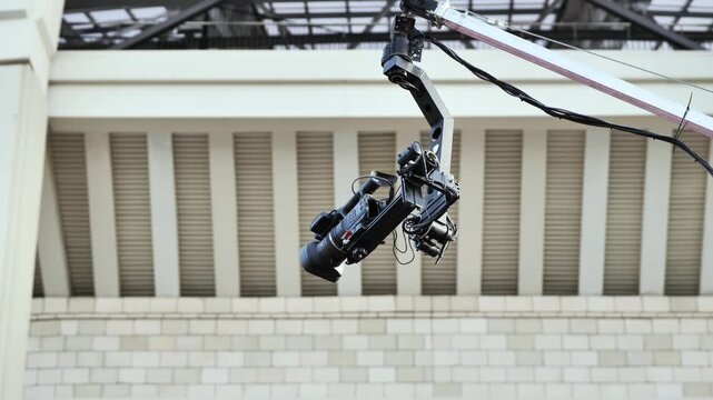 Professional camera crane broadcasting sports event from modern stadium ceiling