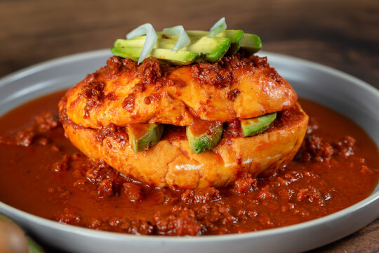 Authentic Mexican pambazo or chancla poblana soaked in red sauce, close-up