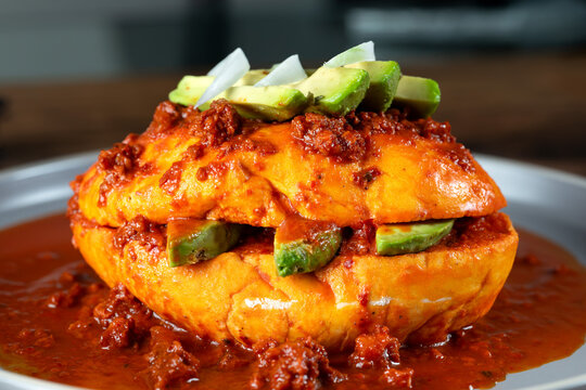 Front view of a gourmet Mexican pabazo with spicy red sauce and fresh toppings, also known as chancla poblana
