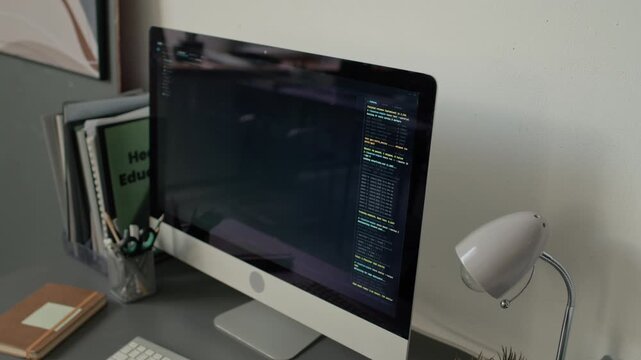 High angle no people close up shot of workstation with monitor displaying code in modern bright office