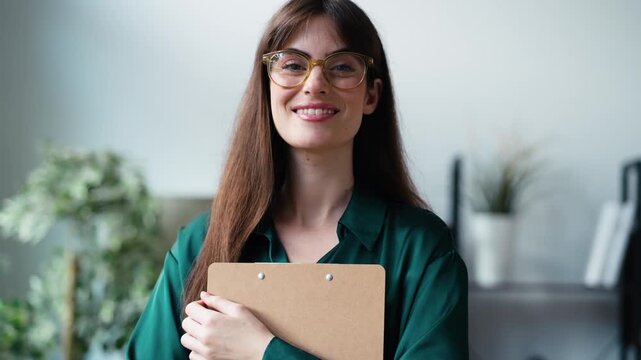 Video of female psychologist holding a folder while posing in front of the camera in her consultation