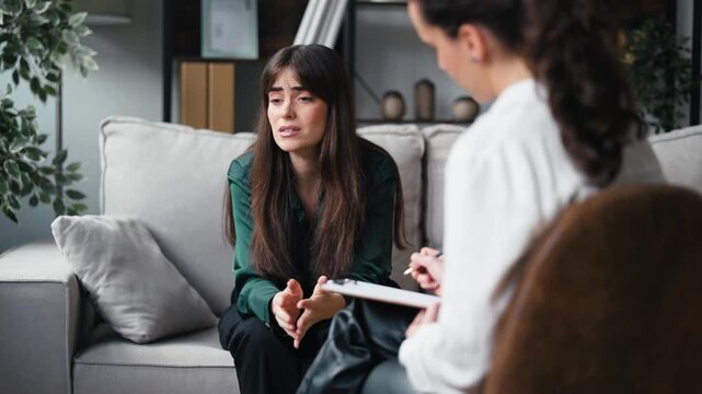 Video of beautiful woman having therapy while the psychologist takes notes, sitting on the couch in the psychology consultation