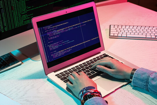 Female programmer's hands working with laptop in office at night, closeup