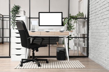 Fototapeta premium Workplace with blank computer monitor near folding screen in office interior