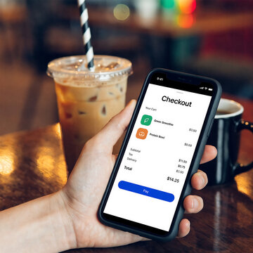 A person holding a smartphone with a mobile payment app open on the screen