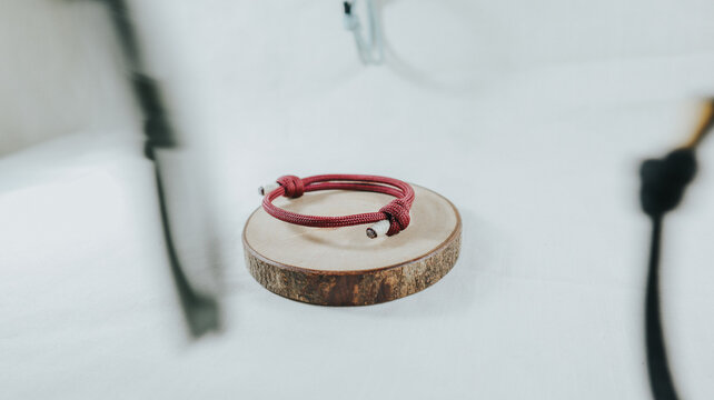 Maroon paracord bracelet on a wooden slice with floating bracelets in motion blur.
